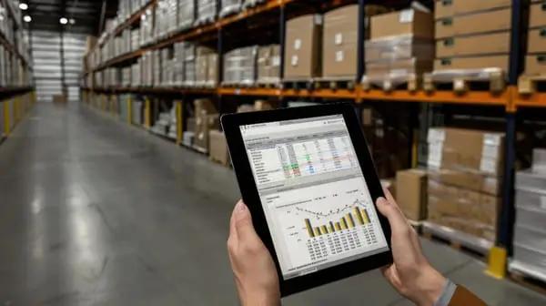 Man using packaging management solutions on his tablet in warehouse.