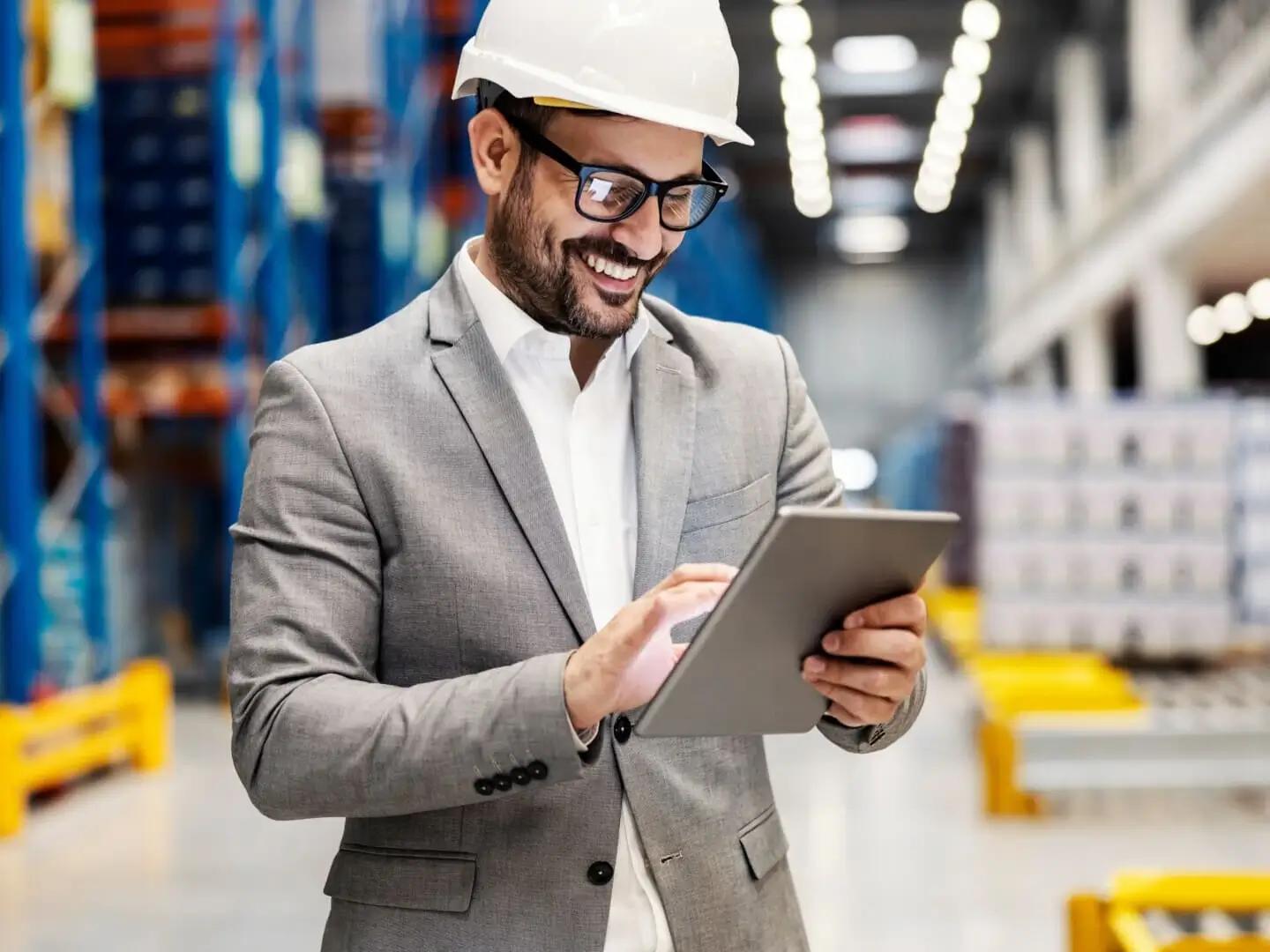 Man in warehouse working on returnable packaging management solutions on a tablet